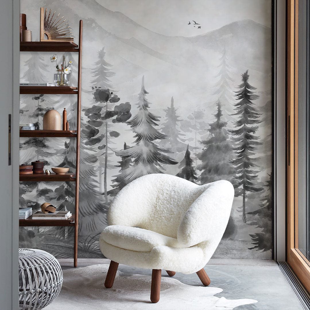 Monochrome Forest Wallpaper in cosy living area with white armchair, natural wood shelving, wood flooring.
