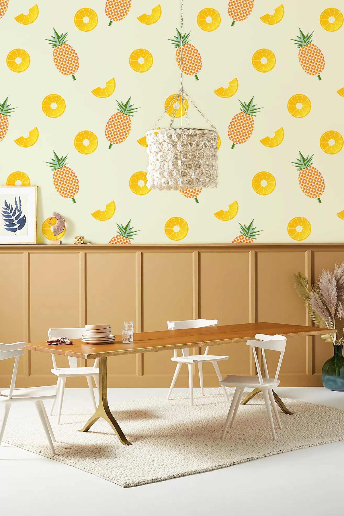 Vibrant pineapple wallpaper with tropical fruit pattern in dining room; wooden table, white chairs, pendant light.