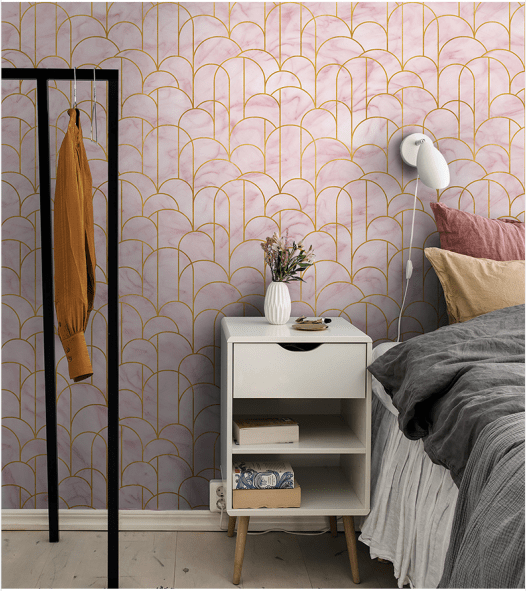 Blush pink geometric wallpaper with gold accents, bedroom setting, light wood flooring, modern decor.