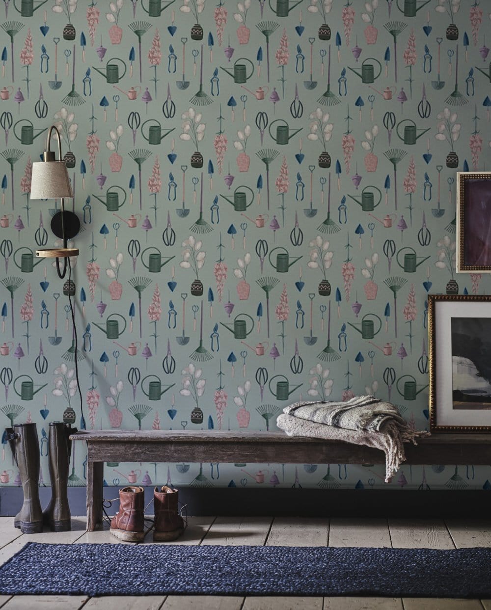 Whimsical pastel garden wallpaper in soft teal, featuring a wooden bench and blue rug in hallway.