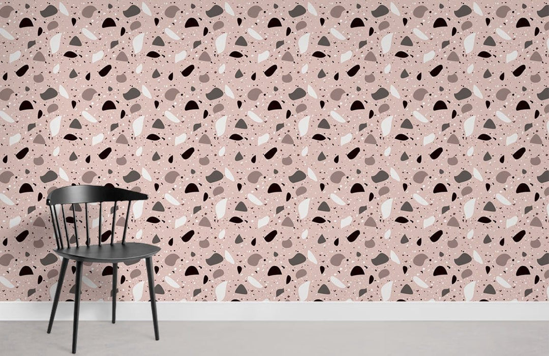 Abstract geometric blush and grey mural wallpaper with black chair on grey flooring in modern room.