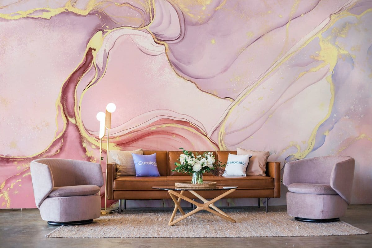 Elegant pastel watercolour marble wallpaper with gold, brown leather sofa, modern chairs, and wooden table.