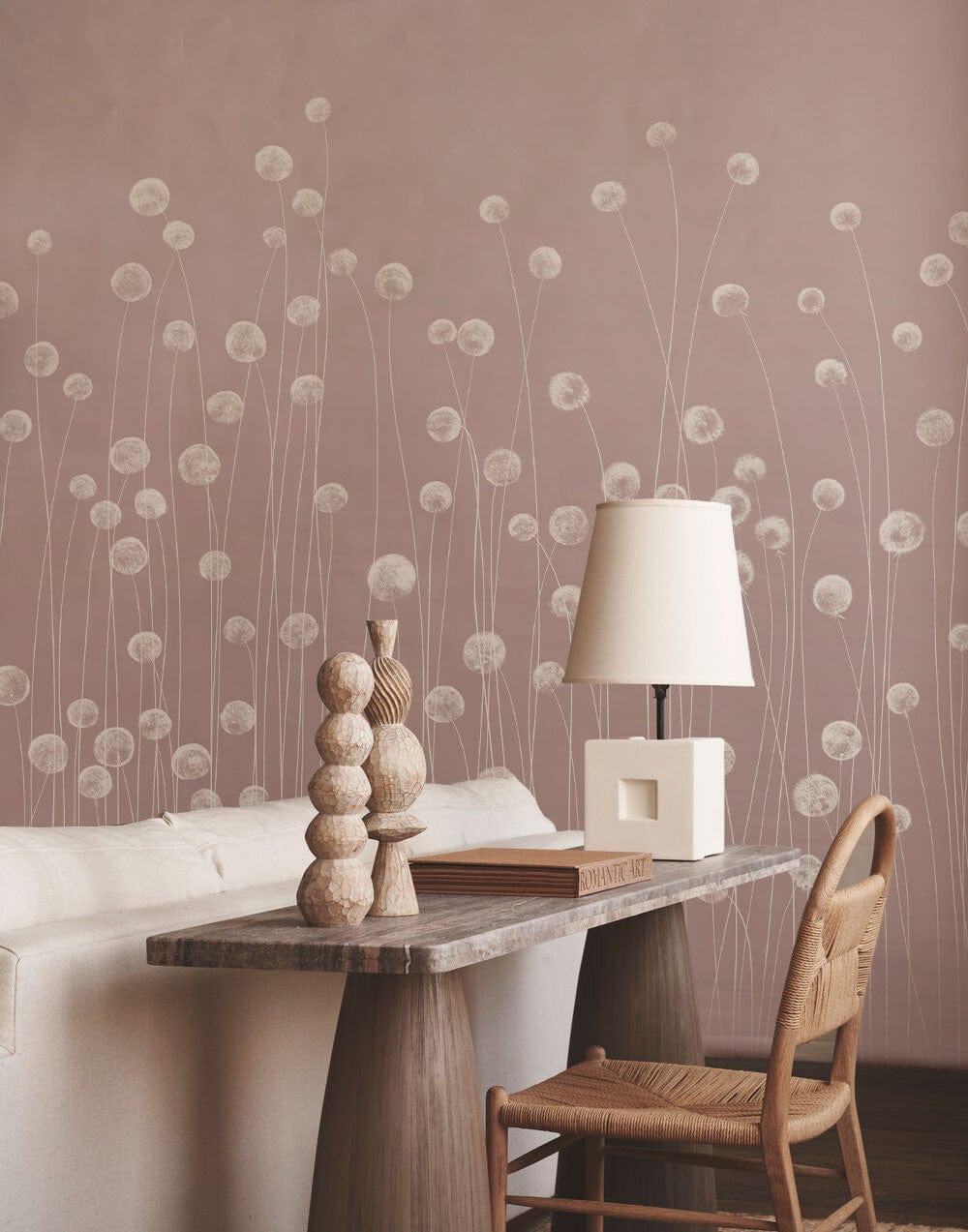 Soft pink wildflower meadow mural wallpaper, beige sofa, rustic chair in elegant living room setting.