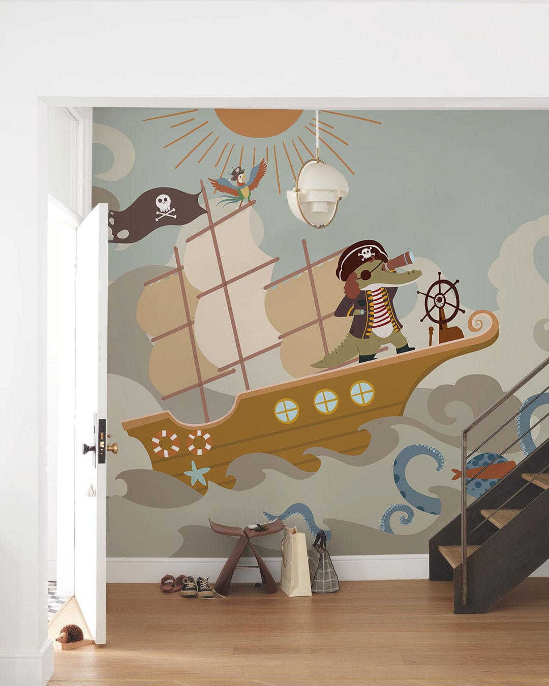 Playful pirate adventure mural wallpaper in children's room, nautical theme, white walls, wood flooring.