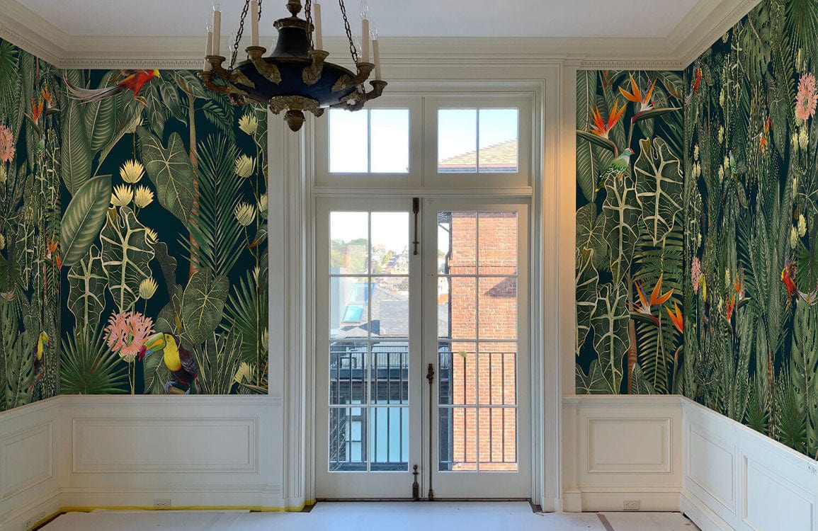 Tropical jungle wallpaper in elegant room with chandelier, white wainscotting, and large windows.