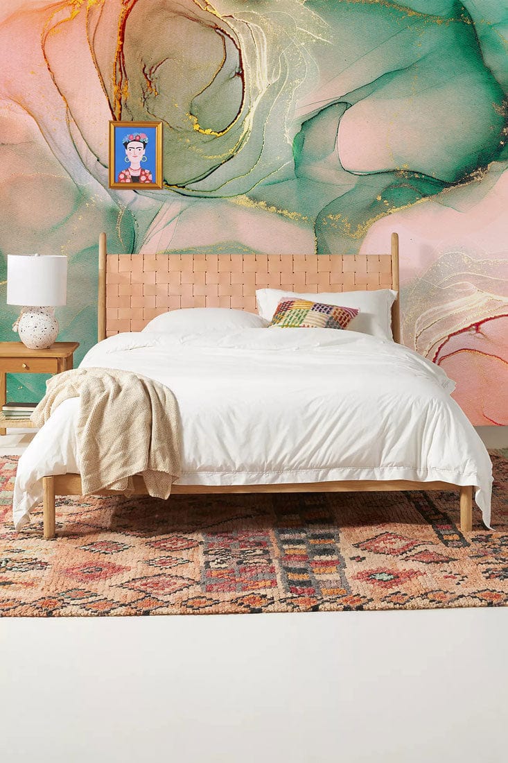 Elegant teal and rose watercolour marble wallpaper with gold accents behind a white bed in bedroom.