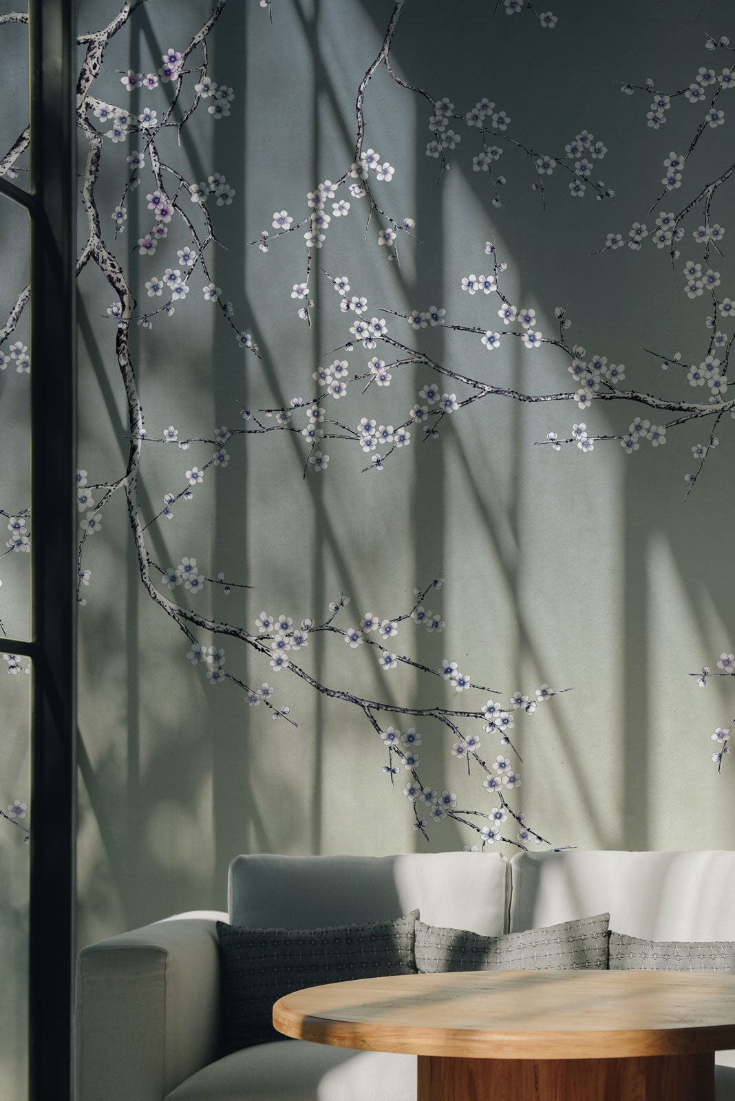 Elegant Blossom Branches mural wallpaper with gradient, white sofa, wooden table, and grey cushions.