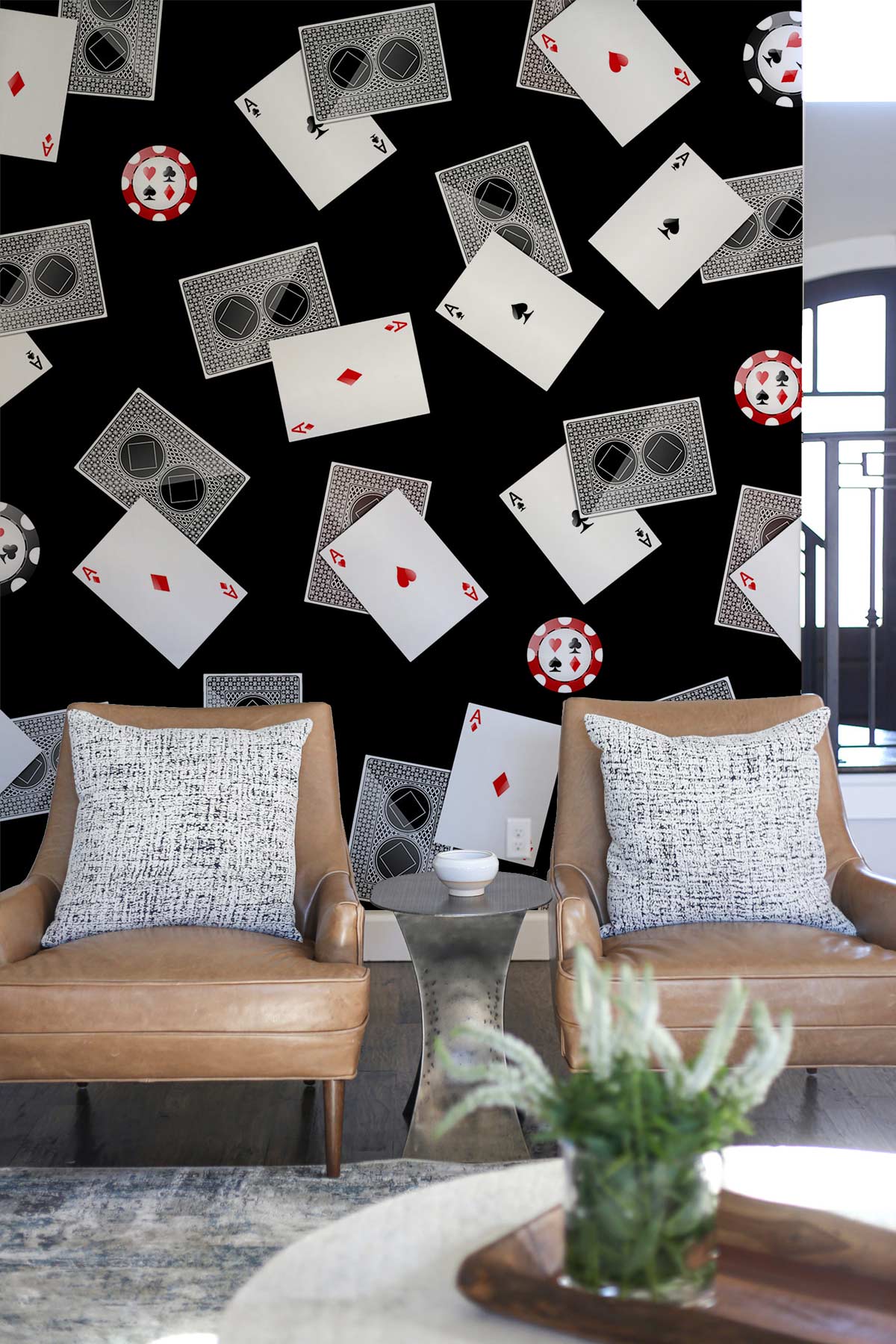 Chic black casino-themed wallpaper with cards, chips; brown leather chairs, grey rug, modern living room.