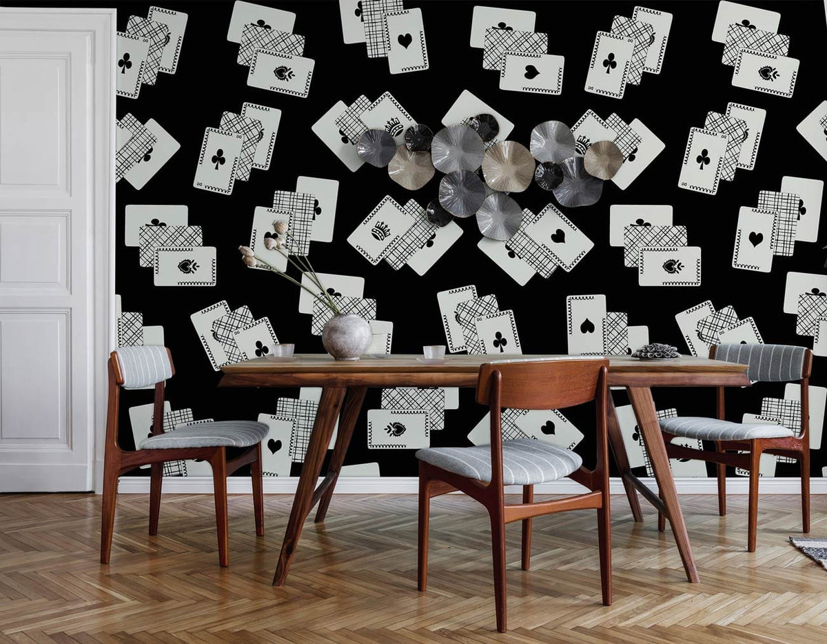 Monochrome playing cards wallpaper in dining room, wooden floor, modern chairs, metallic wall art.