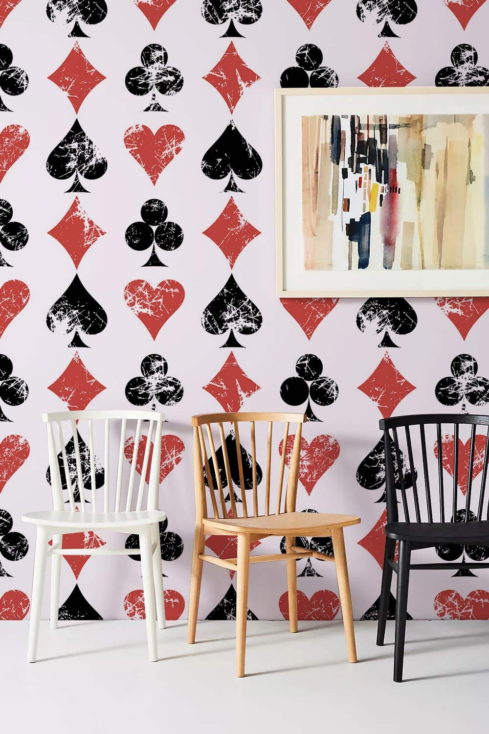 Vintage playing card wallpaper with modern chairs and abstract art in a contemporary living room.