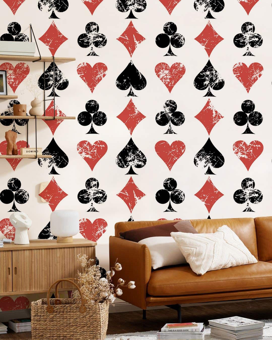 Vintage playing card wallpaper with tan sofa, wicker basket, wood sideboard, and shelves in living room.