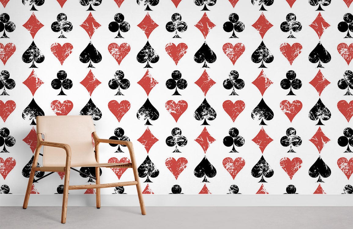 Vintage card-themed wallpaper with black and red patterns; light wooden chair; grey flooring.