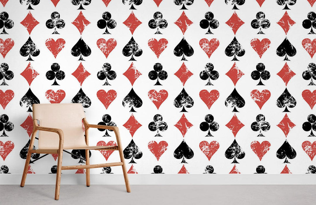 Vintage card-themed wallpaper with black and red patterns; light wooden chair; grey flooring.