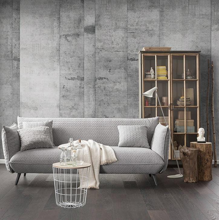 Industrial grey concrete wallpaper, modern sofa, dark wood flooring, glass cabinet, urban living room style.