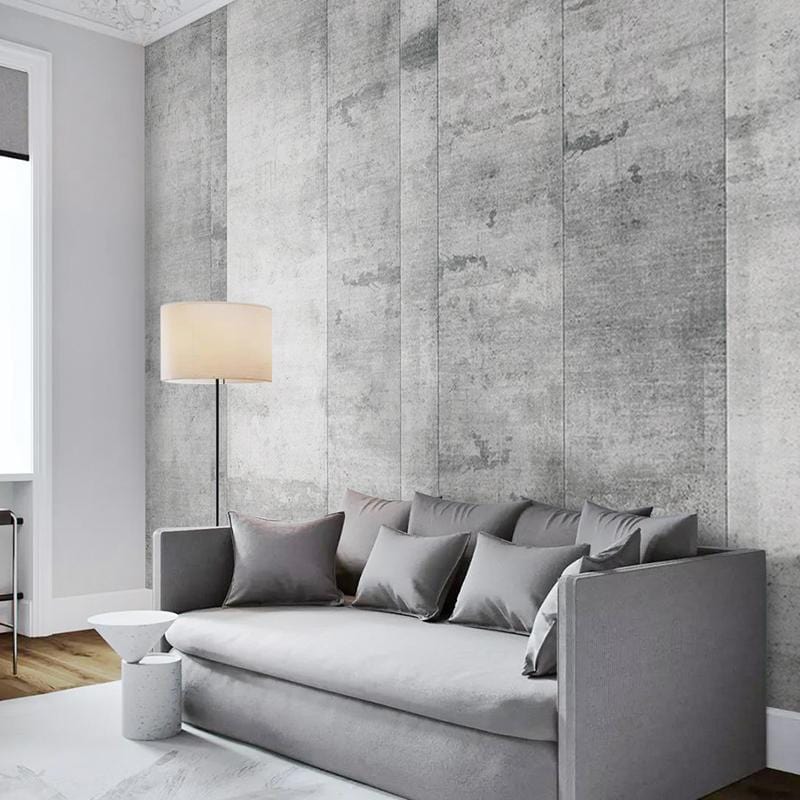 Industrial grey concrete wallpaper in urban living room with grey sofa, wooden flooring, and floor lamp.