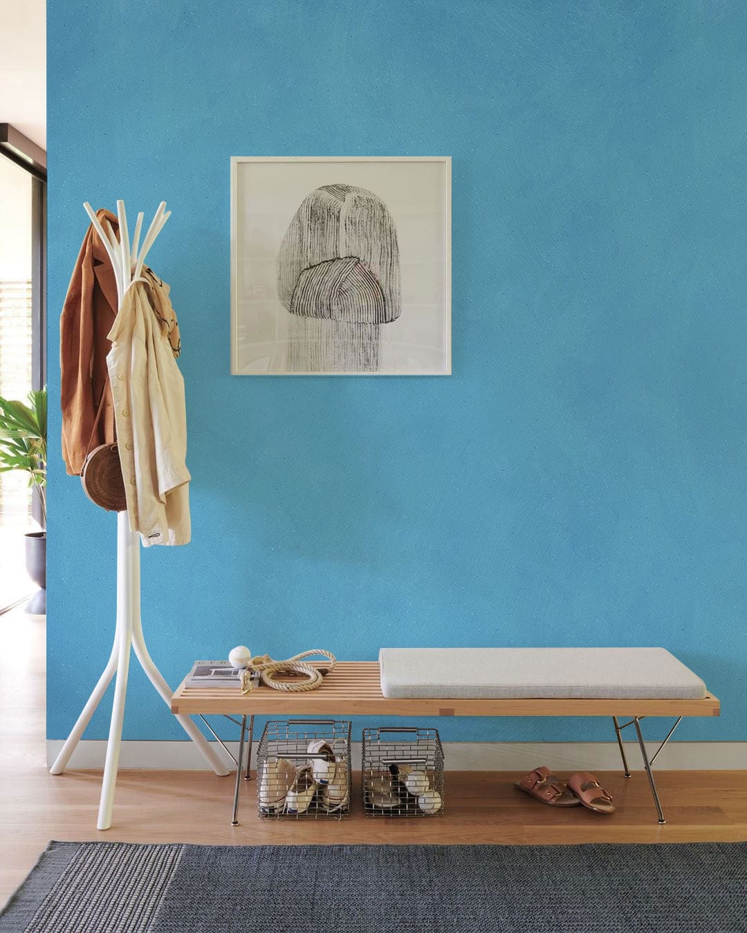 Elegant sky blue textured mural wallpaper, modern bench, coat stand, entrance hall, wooden flooring, artwork.