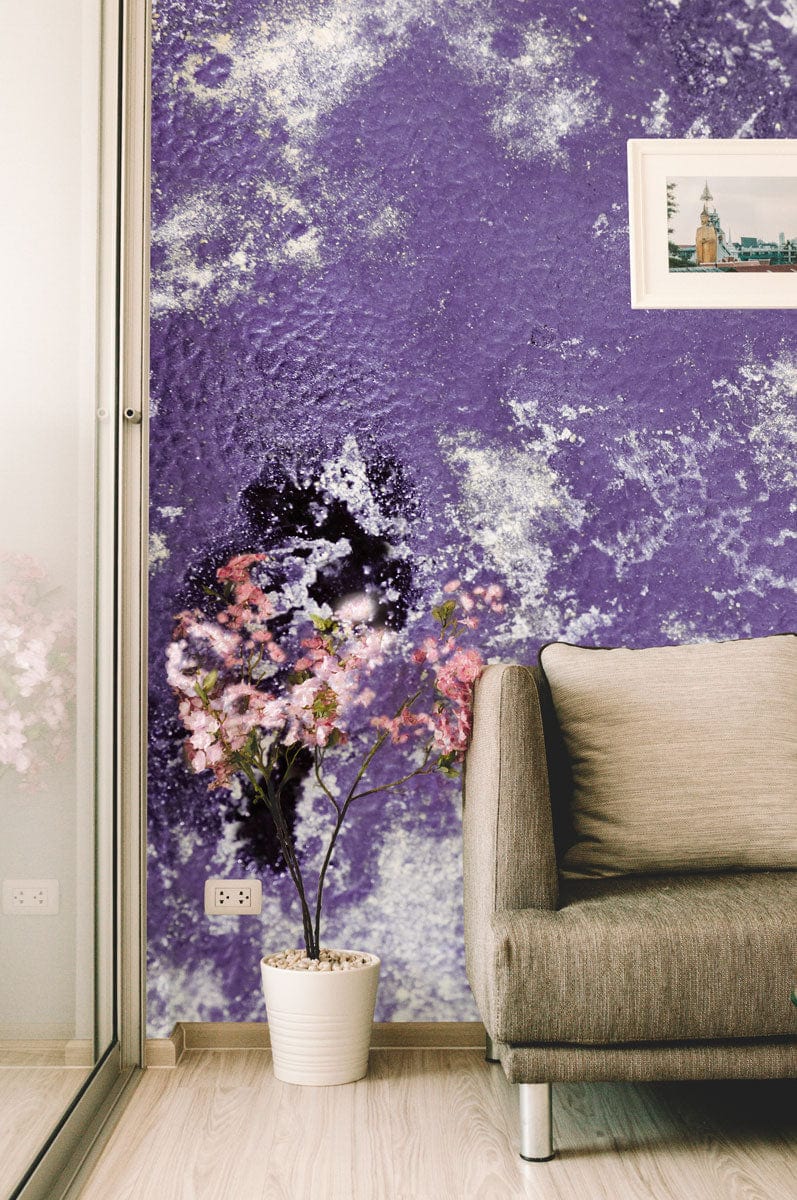 Abstract purple and silver mural wallpaper in modern living room with grey sofa, wooden flooring.