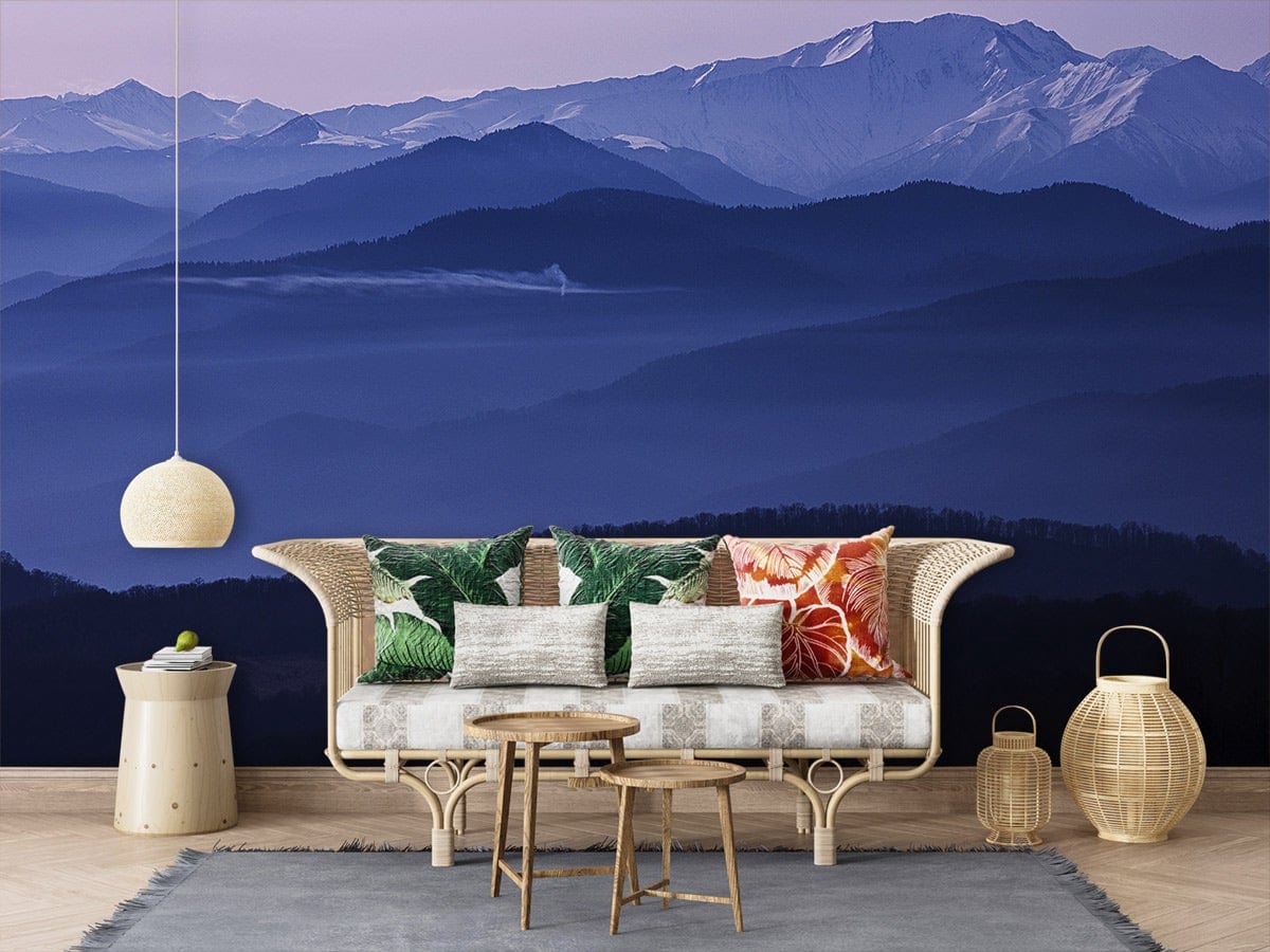 Serene Mountain Mist Blue Landscape Mural Wallpaper, wicker sofa, neutral floor, cosy rug, pendant light.