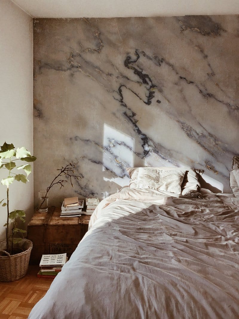 Elegant white marble wallpaper in bedroom with grey bedding and wooden flooring, enhancing luxury decor.