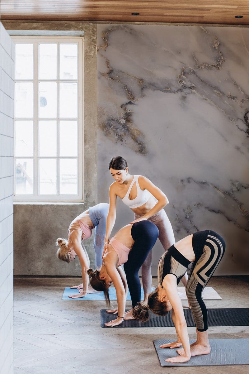 Yoga studio with elegant white marble texture wallpaper and wooden floor, luxury decor UK.