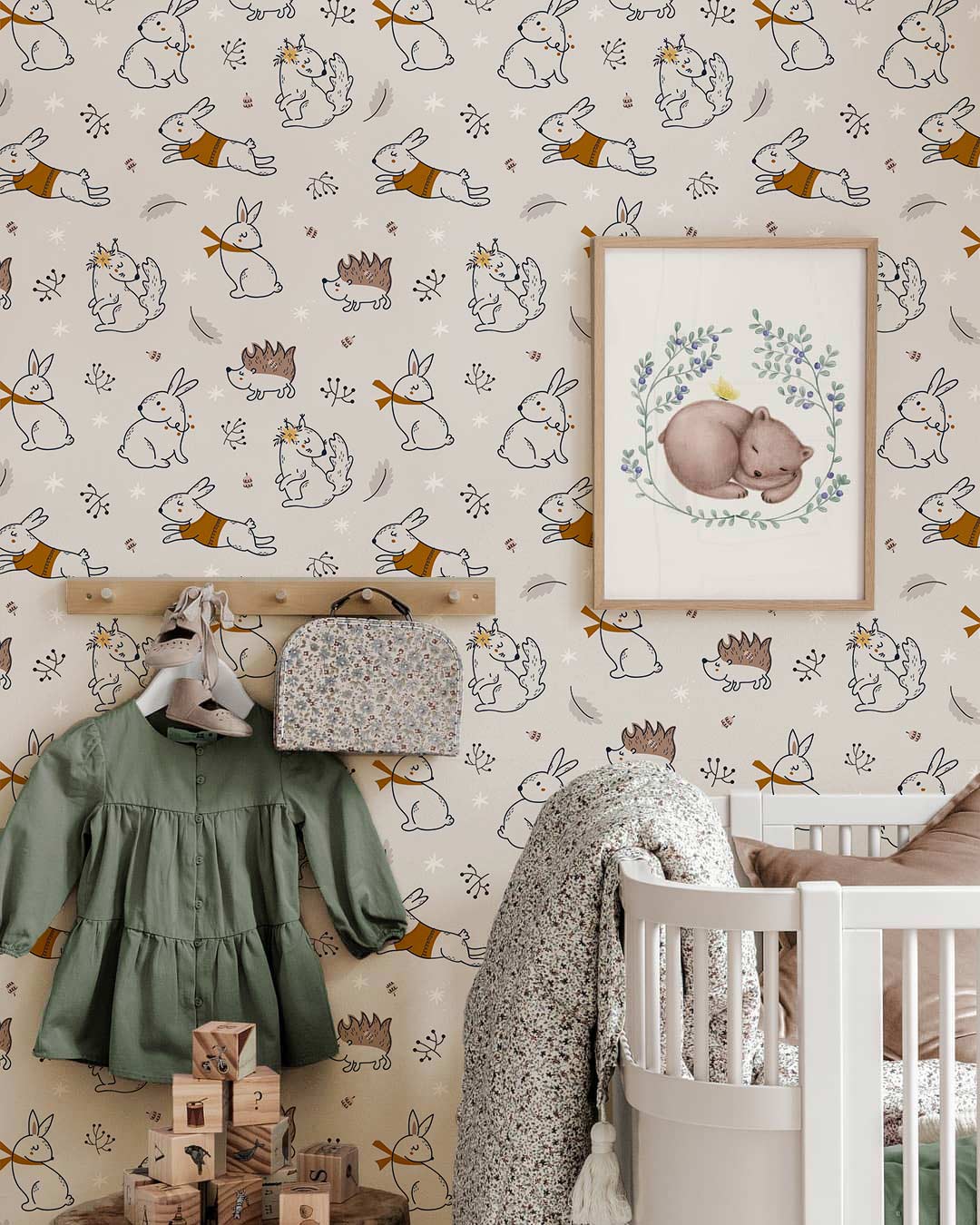 Nursery with woodland wallpaper featuring bunnies, hedgehogs; includes crib, wall art, and clothes rack.