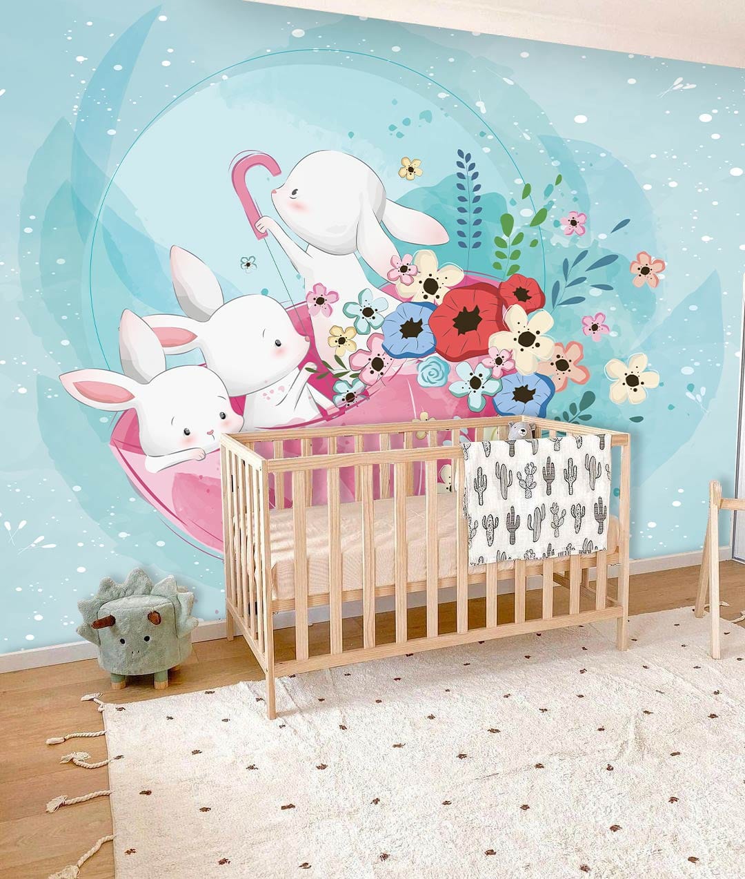 Nursery features Whimsical Pastel Bunny Garden Mural Wallpaper, floral accents, wooden cot, playful rug.