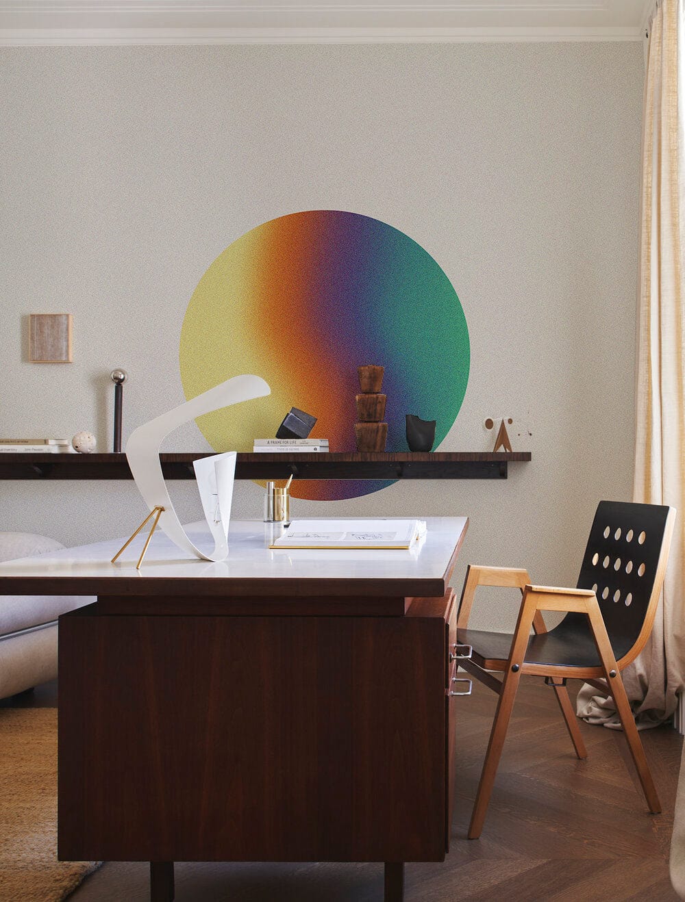 Modern office with wooden desk, contemporary chair, neutral wall, and colourful circular wall art.