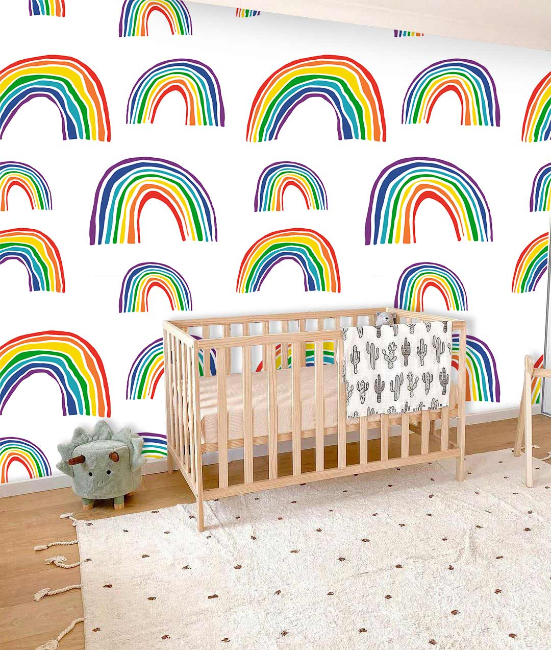 Vibrant rainbow wallpaper patterns in colourful kids' room with wooden crib and plush carpet flooring.