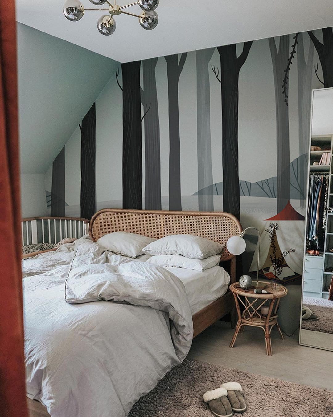 Wintry Forest Mural Wallpaper in bedroom, grey woods, cosy bed, rattan furniture, warm atmosphere.