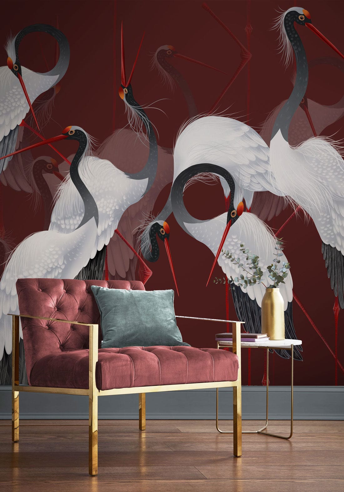 Elegant Crane Dance mural wallpaper, rich red; pink velvet armchair, gold frame, hardwood flooring, modern decor.