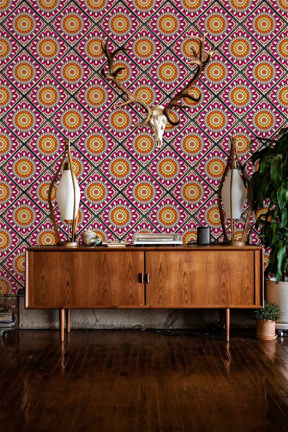 Vibrant retro geometric wallpaper with wooden sideboard, antlers, and patterned floor, offering vintage charm.