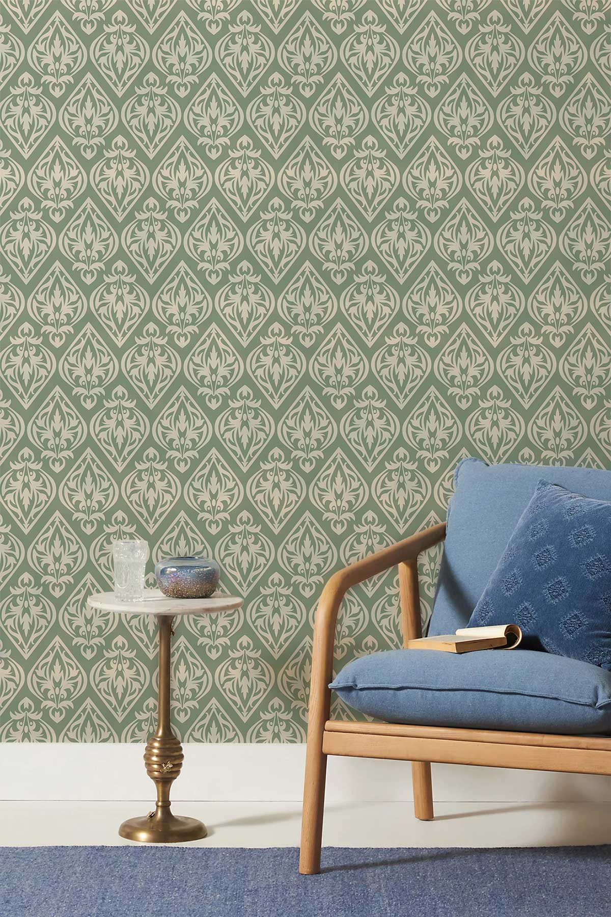 Victorian-inspired sage green damask wallpaper, blue armchair, marble side table, stylish room decor.