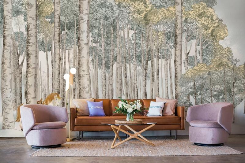 Brown leather sofa, round chairs, forest mural wallpaper with horse, wood flooring, bright floor lamp.