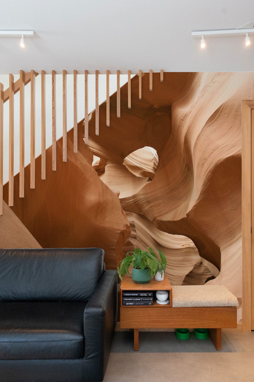 Desert Canyon Elegance Mural Wallpaper in earth tones, black leather sofa, wood accents, modern interior.