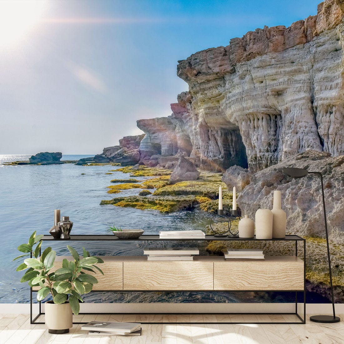 Coastal Cliff Serenity Mural Wallpaper: Seaside rocks scene, modern room, wooden sideboard, plant decor.