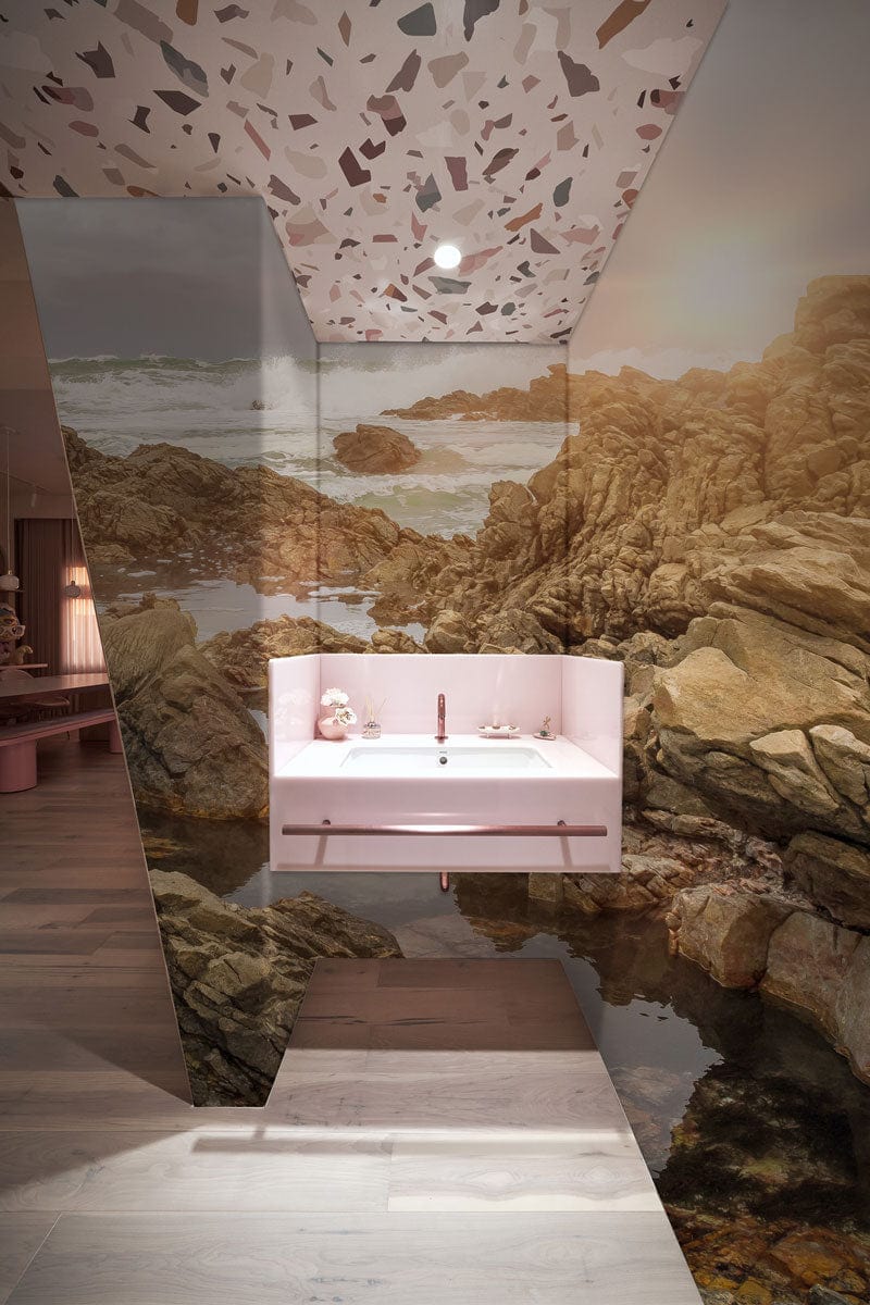Sunlit rocky coastline mural wallpaper with terrazzo ceiling in modern bathroom, light wood flooring.