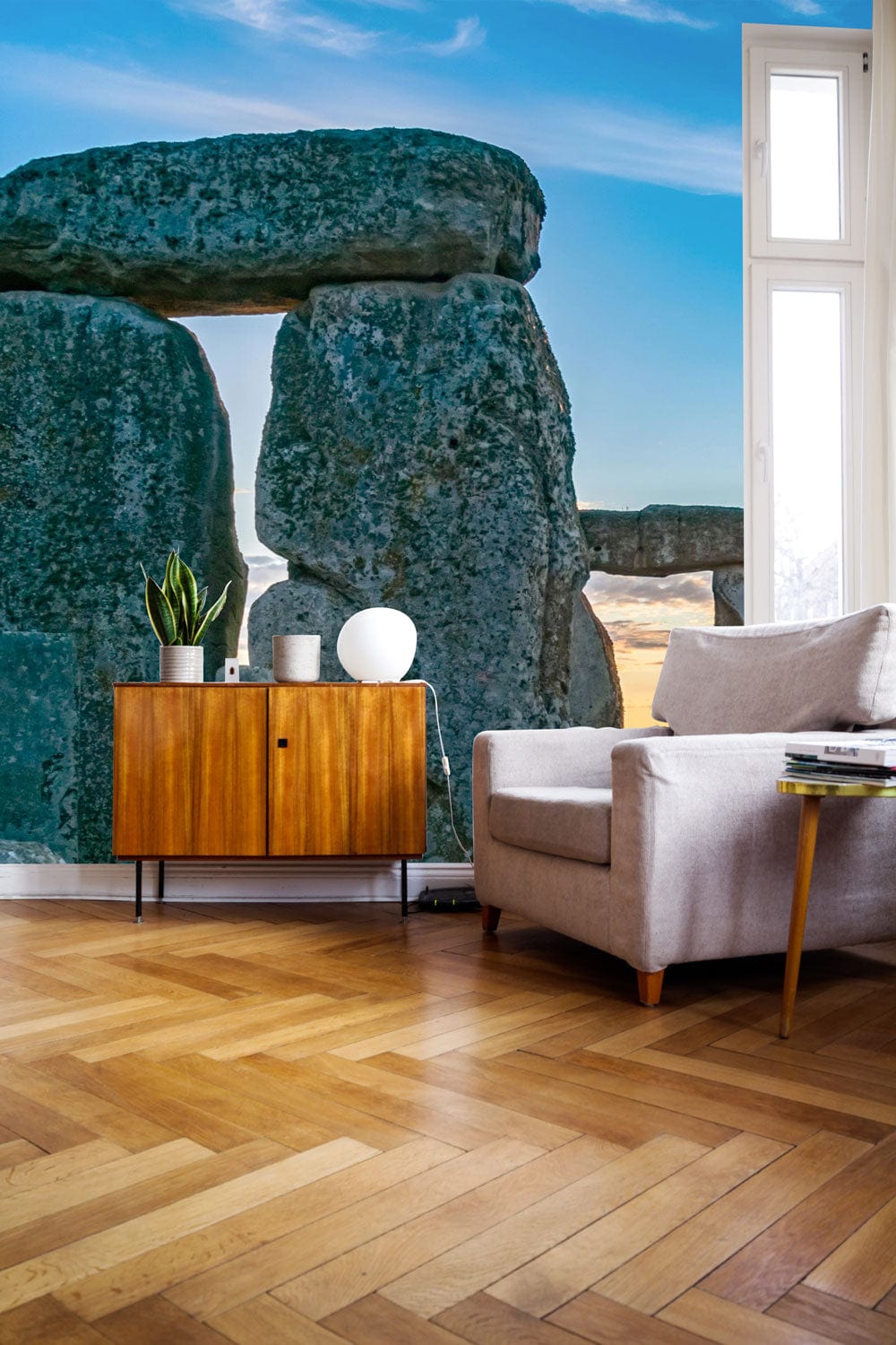 Sunlit Stonehenge Scenic Mural Wallpaper in lounge, grey sofa, wooden cabinet, parquet flooring.