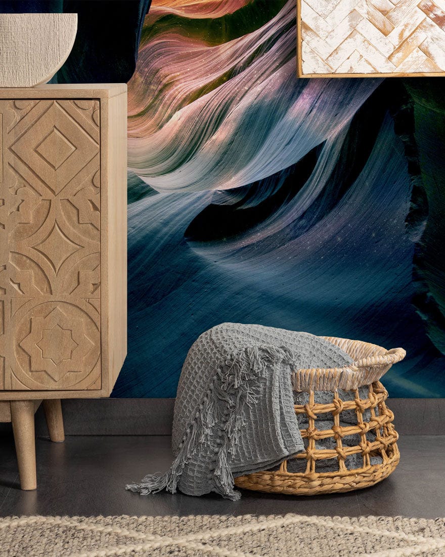 Abstract Canyon Wave mural in blue, purple, peach with ornate cabinet, woven basket, grey throw.