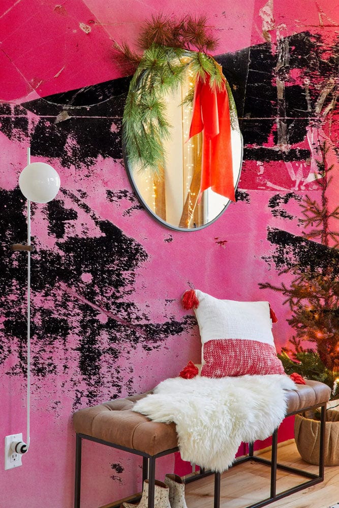 Vibrant pink graffiti wallpaper, brown bench, mirror, and festive decor in modern living room setting.