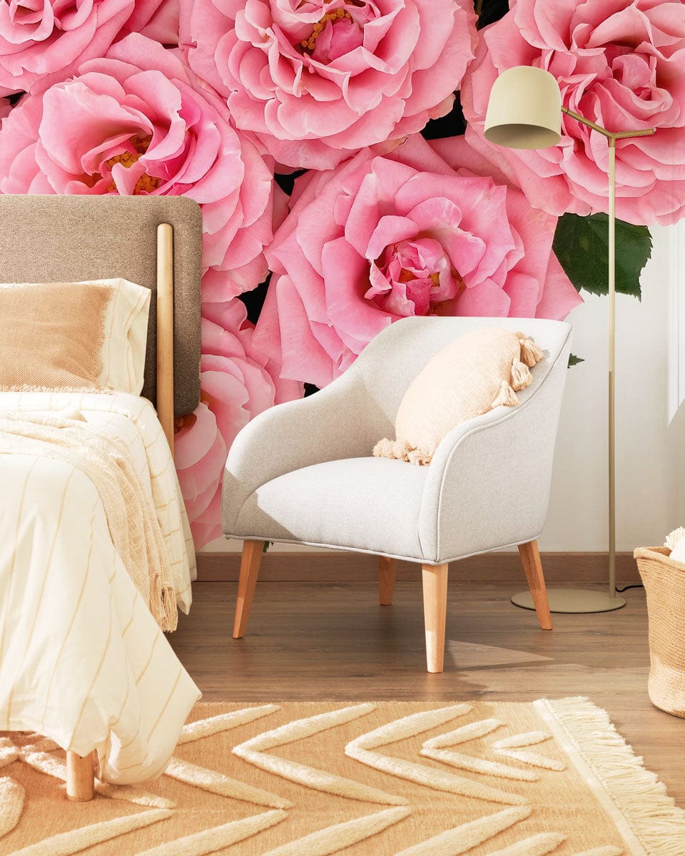 Elegant Pink Roses Wallpaper in bedroom with modern grey armchair, wooden flooring, and beige accents.
