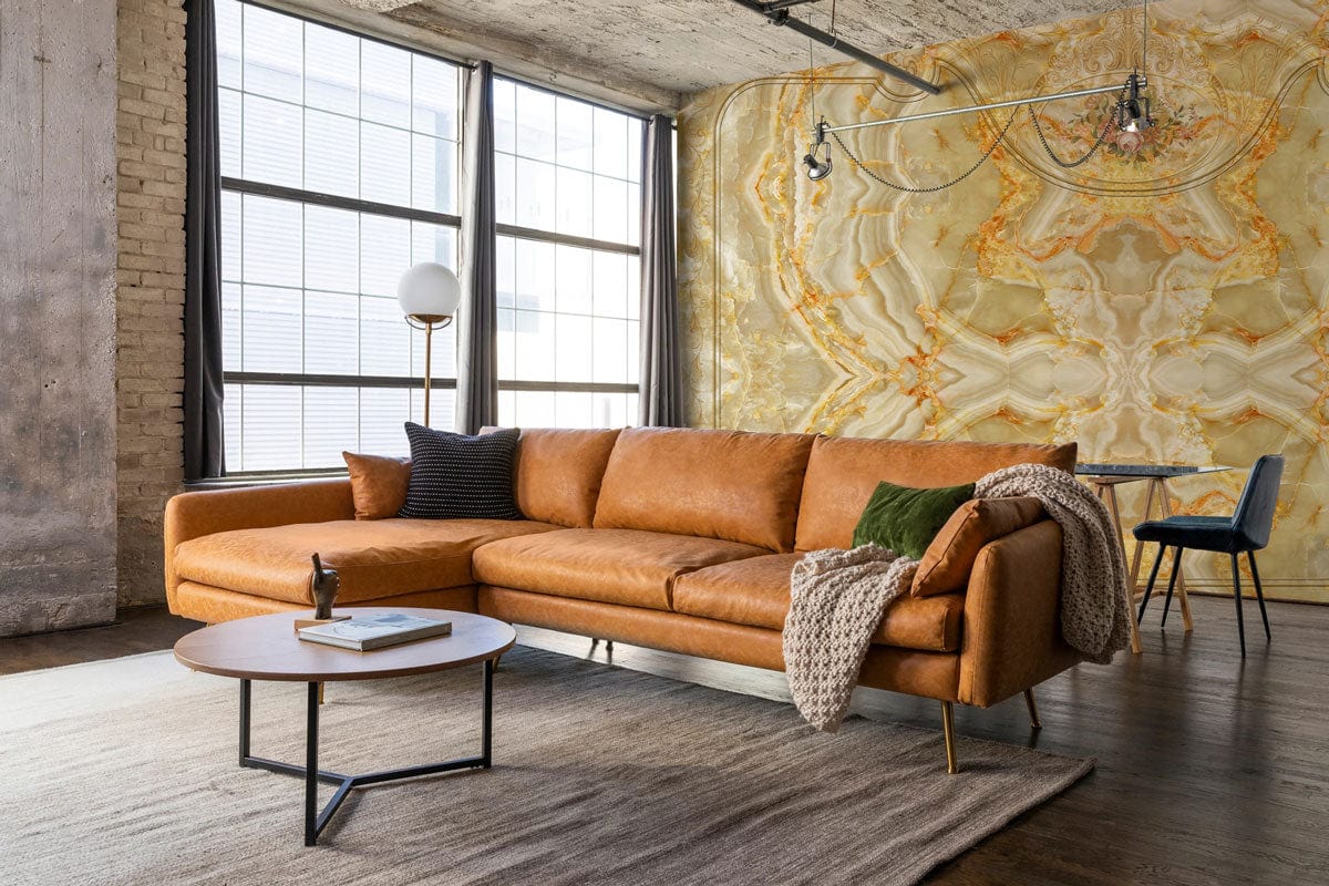 Elegant golden marble texture mural wallpaper behind brown leather sofa in modern living room setting.