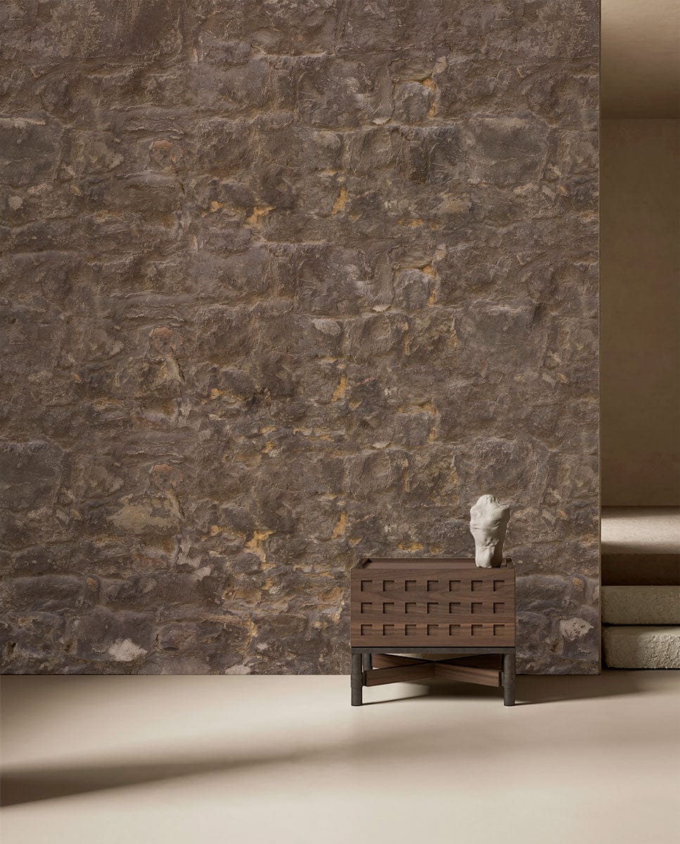 Rustic brown stone brick wallpaper, decorative sculpture, minimalist table, complementing neutral flooring in interior.