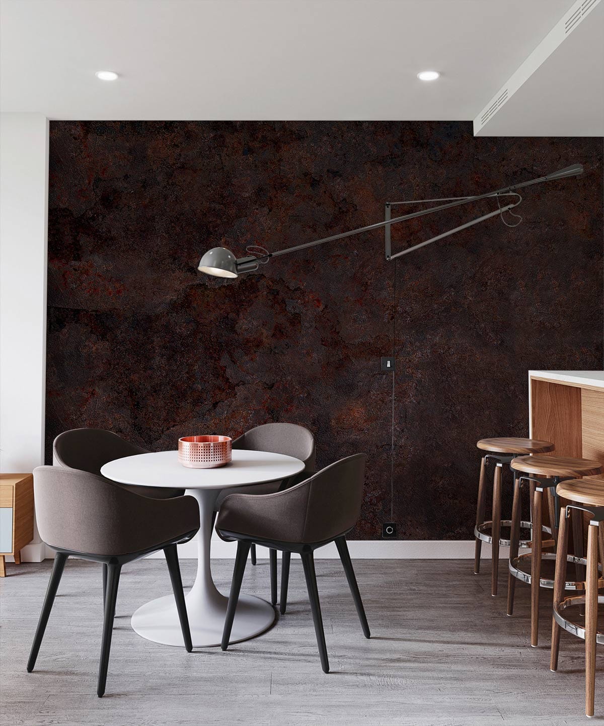 Rustic industrial brown stone effect wallpaper in modern kitchen with grey chairs, wooden stools, round table.