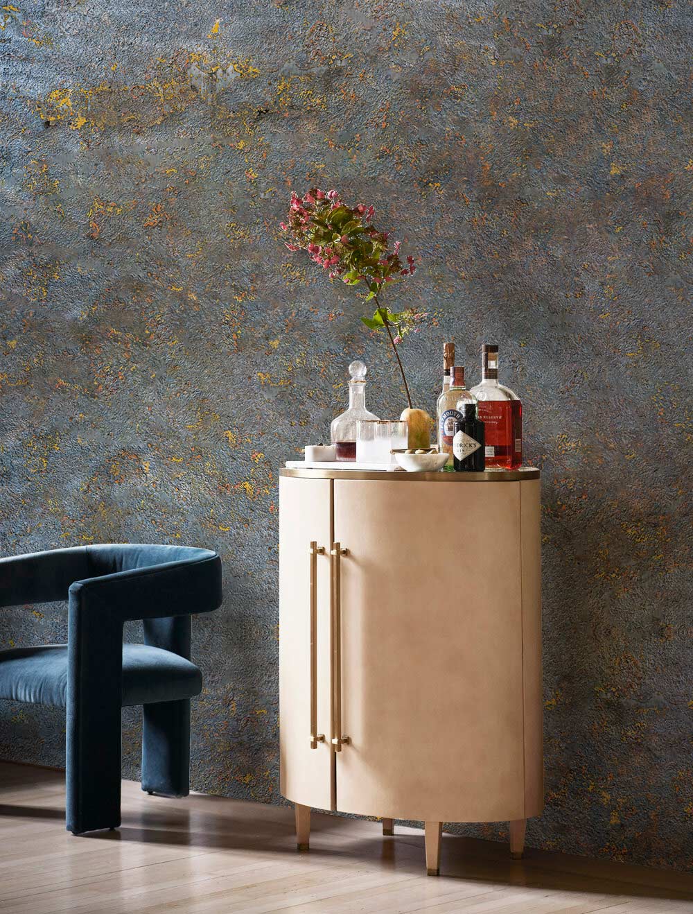 Vintage industrial blue and gold mural wallpaper, rustic decor, velvet armchair, minimalist cabinet, wood flooring.