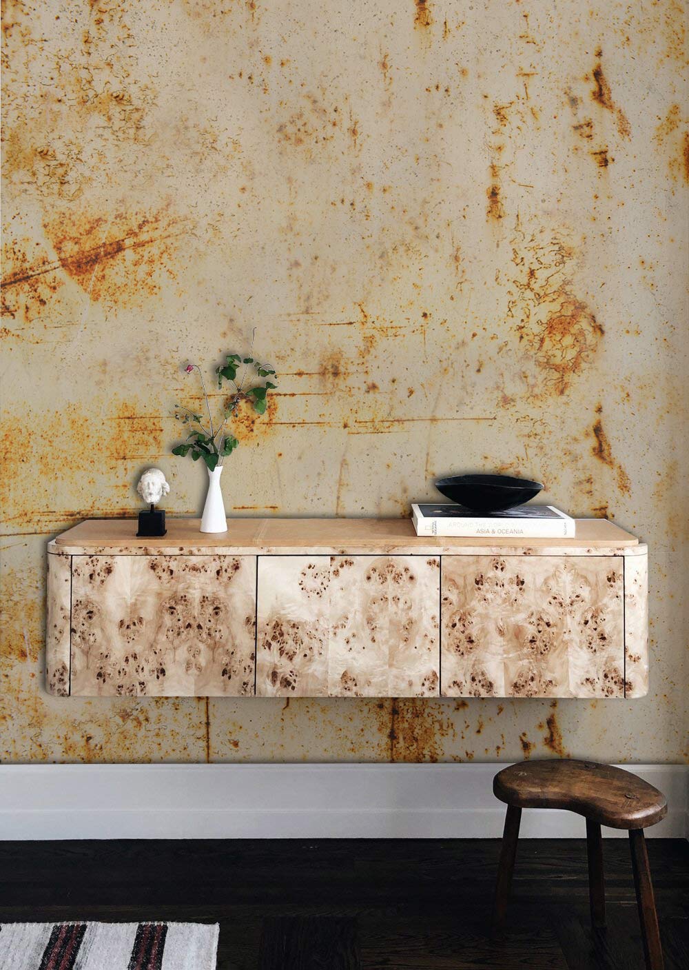 Vintage rust wallpaper with industrial aesthetic; earthy tones complement wooden stool, console, dark flooring.