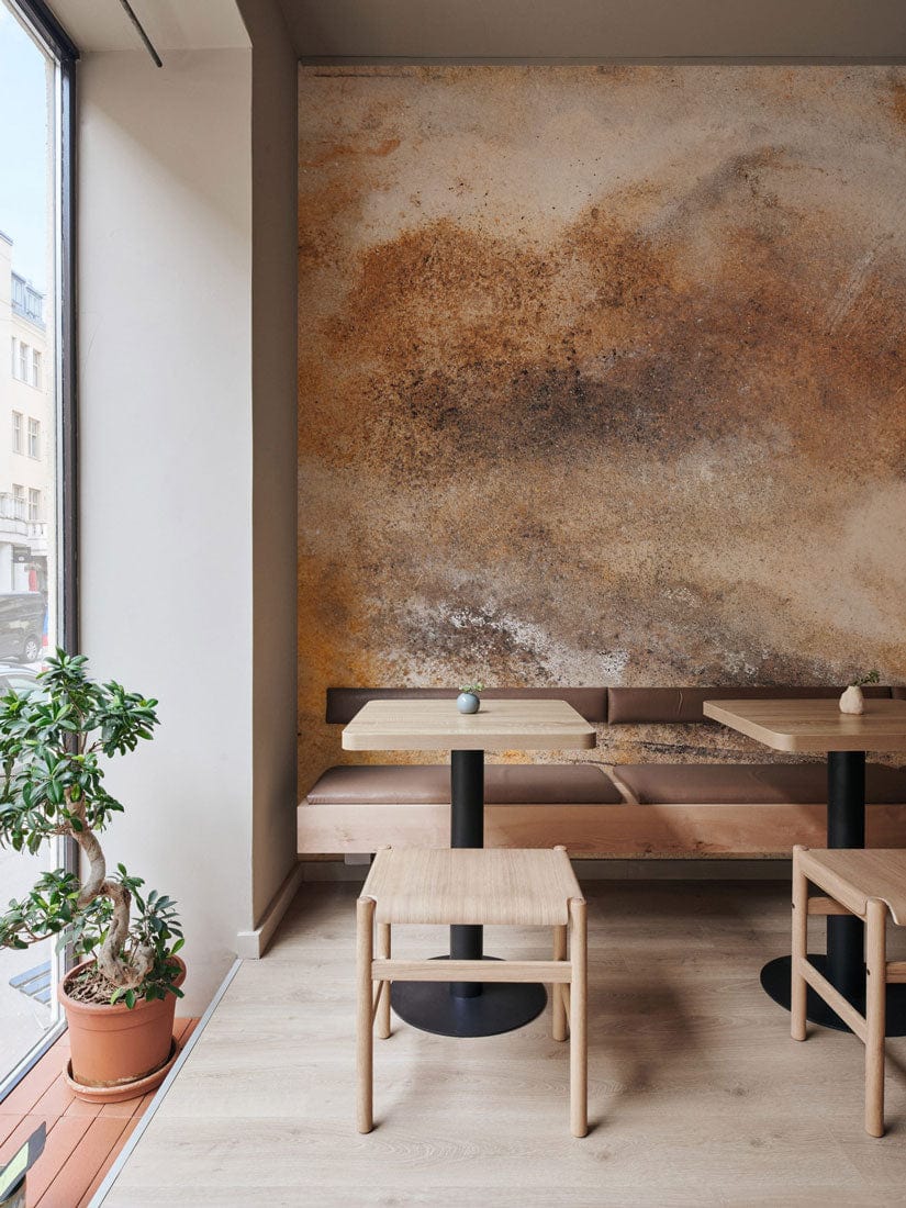 Rustic Earth Tones Abstract Art Mural Wallpaper in café with wooden tables, benches, light wood flooring.