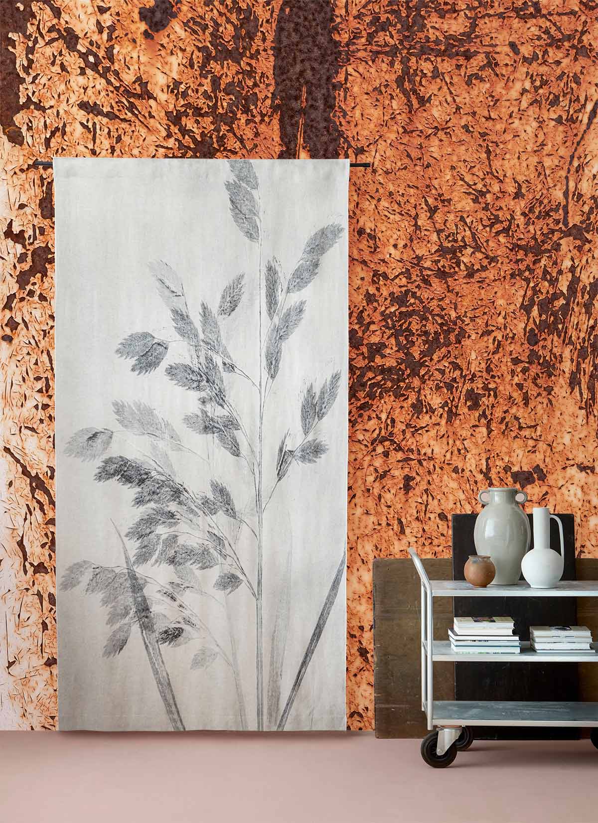 Rustic copper textured abstract mural wallpaper in earthy tones, decorated living room with vases and books.