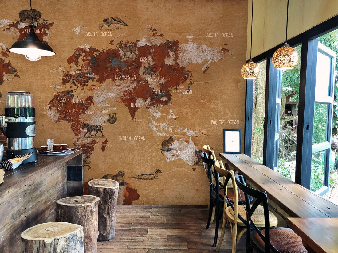 Vintage Earth Tones World Map Mural Wallpaper, rustic café with wooden stools, large glass windows.