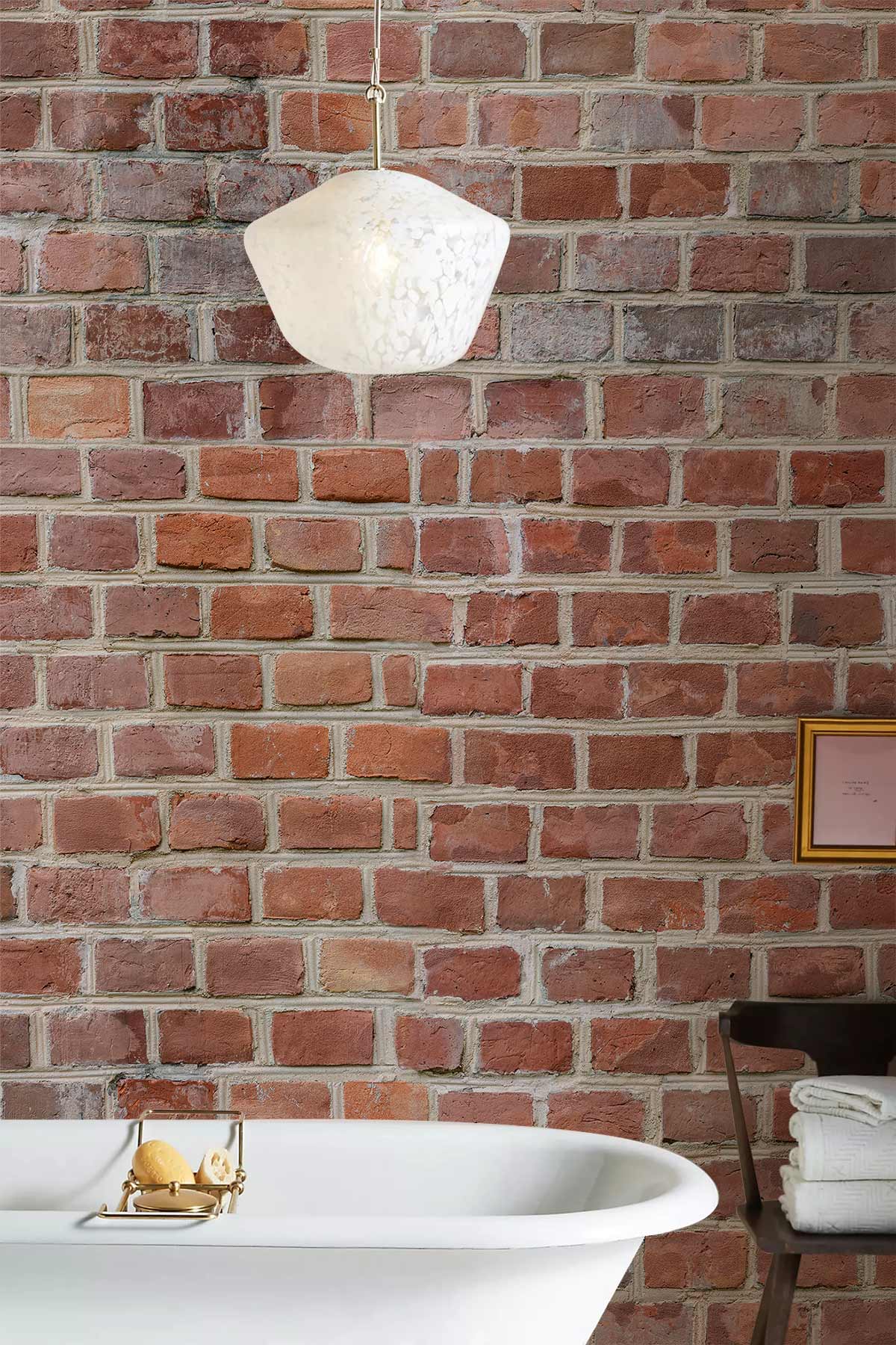 Rustic red brick wallpaper in bathroom with white pendant, vintage tub, and brown chair.