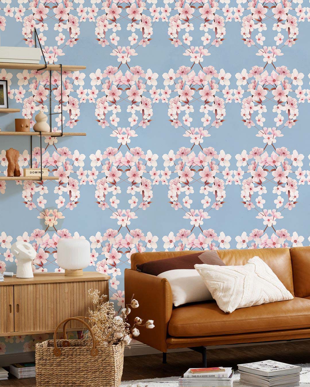 Elegant floral damask wallpaper, blue and pink; brown leather sofa; rattan basket; wooden sideboard.